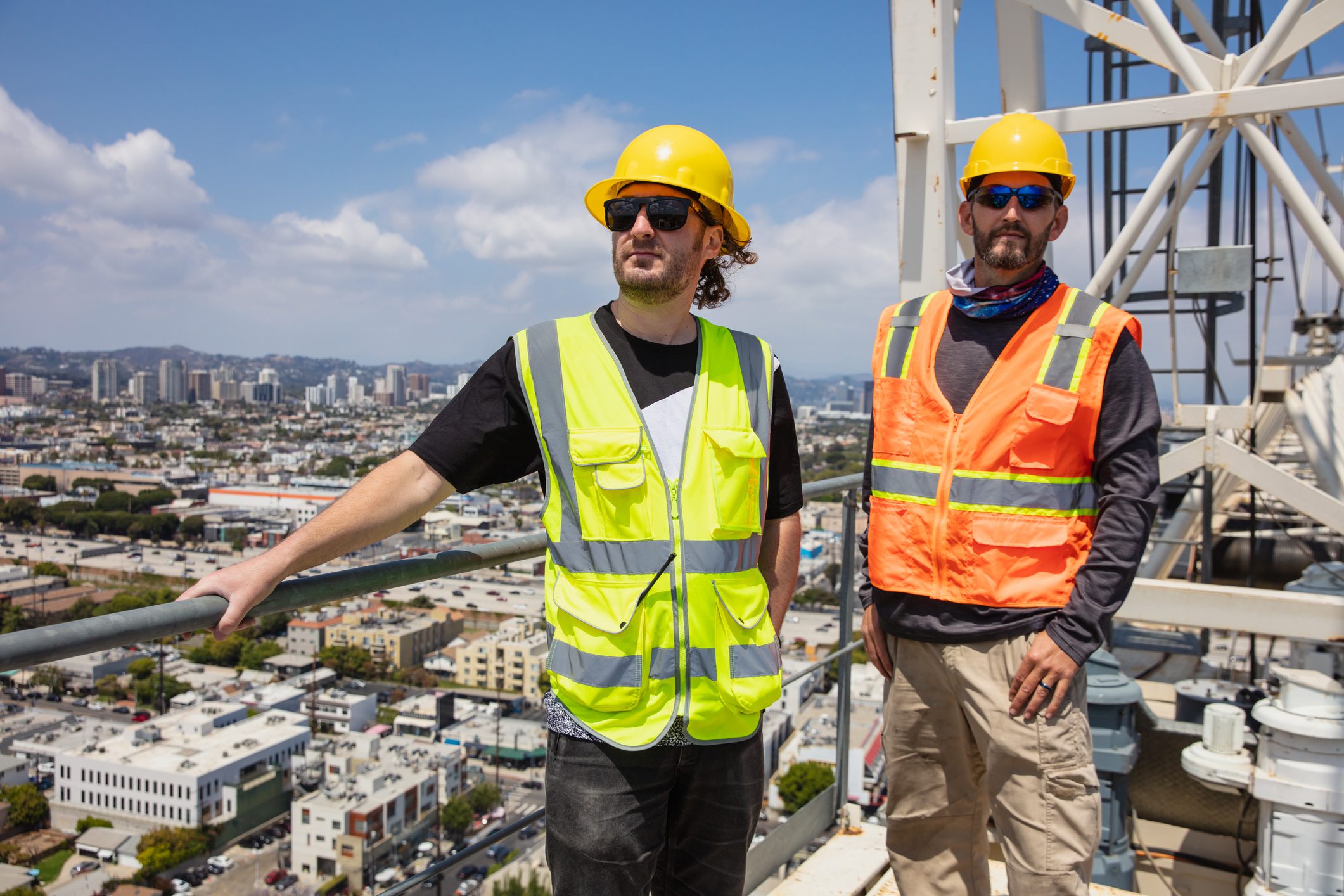 Construction workers on rooftop with city view.